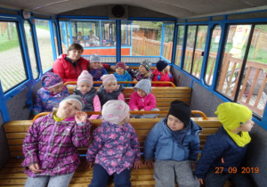 Dzieci siedzą w wagonach kolejki.